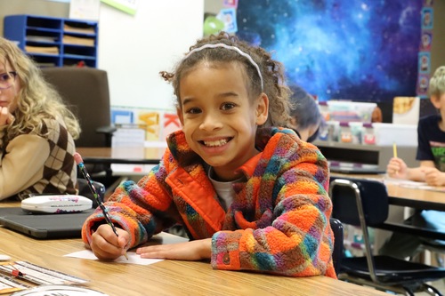 A student smiles at the desk