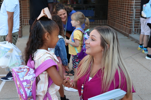 A teacher greets a student