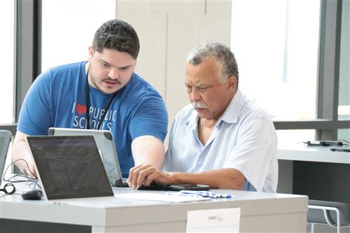 A staffer helps another with a computer