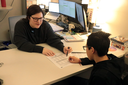 A counselor works with a student on paperwork