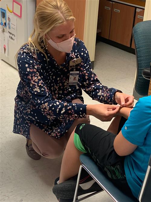 School Nurse Placing bandaid on students arm