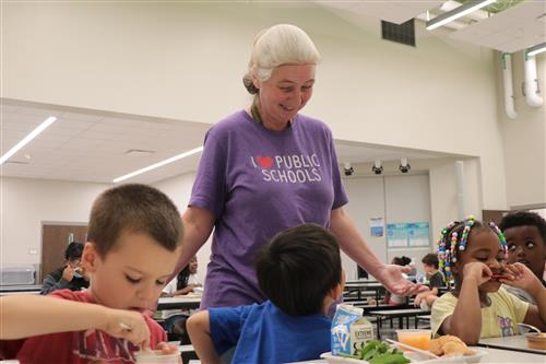 A staff member looks over students eating lunch