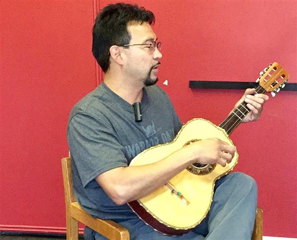 A ma holds a vihuela guitar