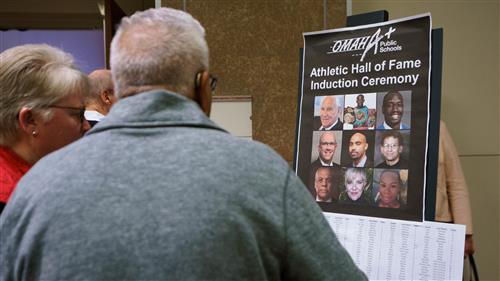 Individuals look at a poster of hall of fame inductees