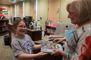 student giving book to teacher