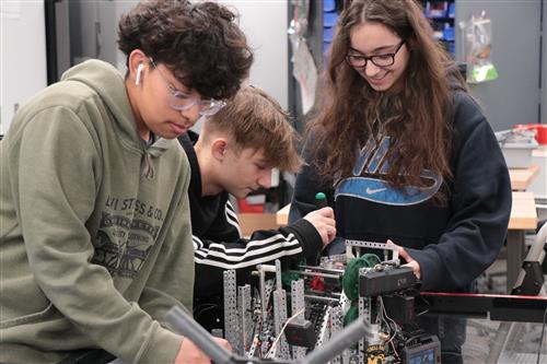 Three students work together engineering a robot